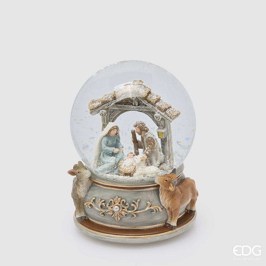 Sfera d'acqua natalizia con carillon della Natività firmata EDG Enzo De Gasperi, alta 16,5 cm. Cupola in vetro con Sacra Famiglia e base grigio-blu decorata in oro con bue e asinello tridimensionali.