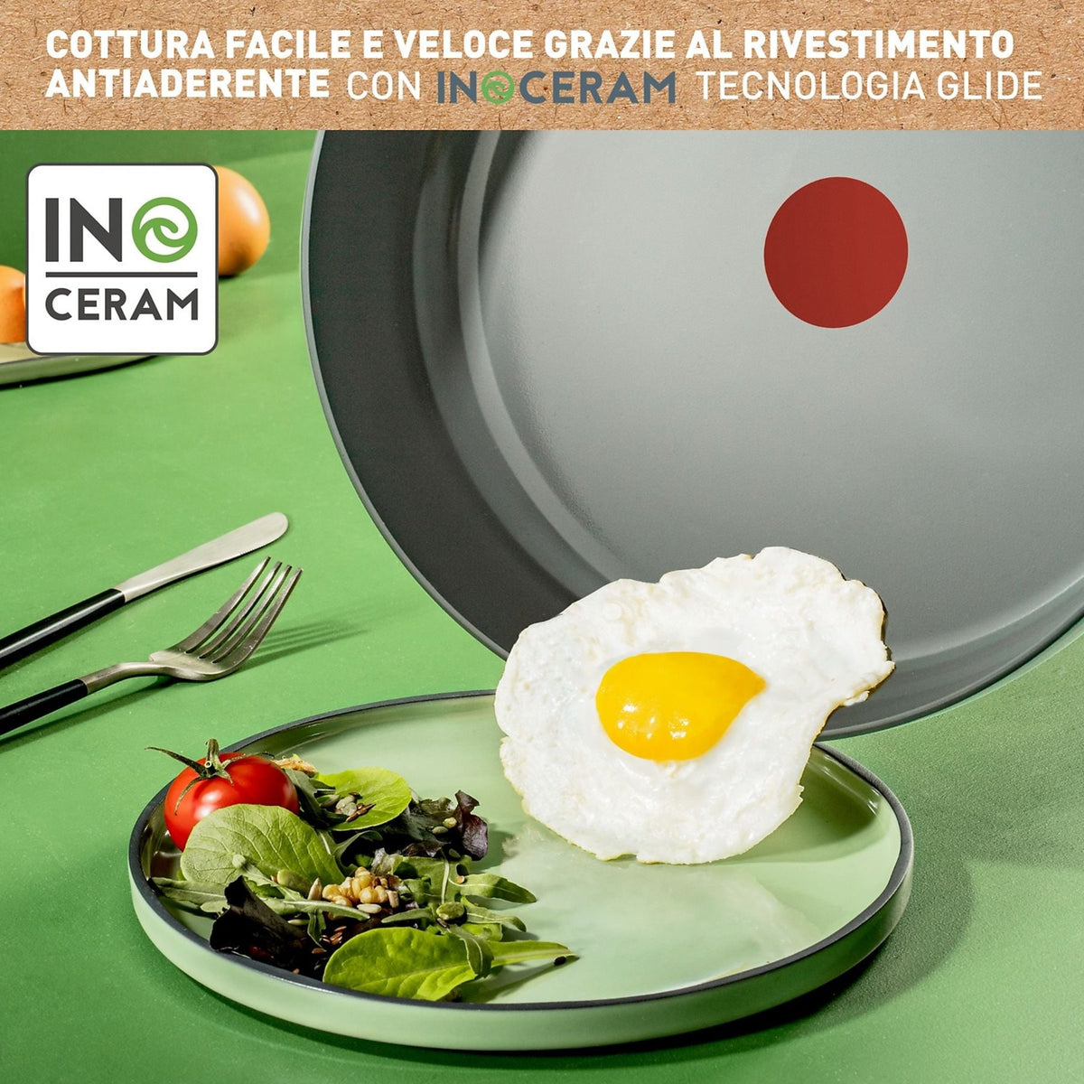 Dettaglio della cottura su padella in ceramica Lagostina con tecnologia Inoceram Glide e bollino rosso Thermo-Signal, mentre un uovo all'occhio di bue scivola perfettamente verso un piatto con insalata e pomodorini, Tutto Chic.