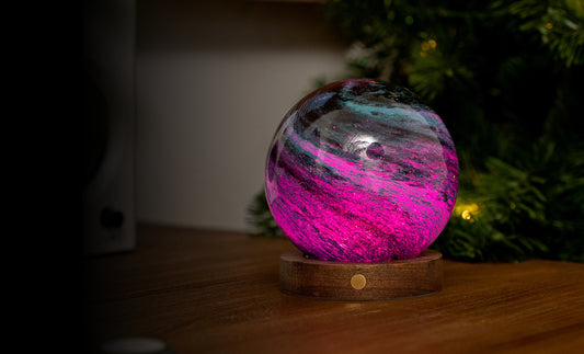 lampada AstraGlass Light. Composta da una sfera in vetro soffiata e dipinta a mano poggiata su una base rotonda in legno di noce americano. Questa lampada è perfetta per chiunque sia affascinato dal meraviglioso fenomeno naturale del nostro mondo. Dimensioni: cm ø 12 x h 13. In negozio e online su tuttochic.live