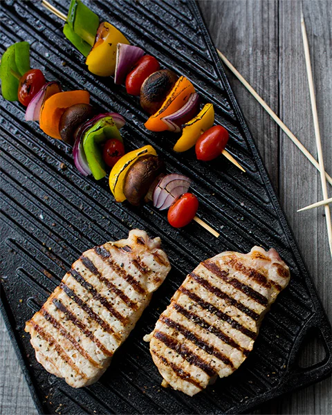 la Piastra Reversibile Lodge. Il lato liscio è ideale per cuocere panini, pancakes, uova e tanto altro. Il lato a coste è adatto invece per grigliare carne, pesce e verdure di ogni tipo. Resiste alle altissime temperature. Dimensione: 42,55 x 24,13 x 1,57 cm• Peso: 4,25 kg. In negozio e online su tuttochic.live