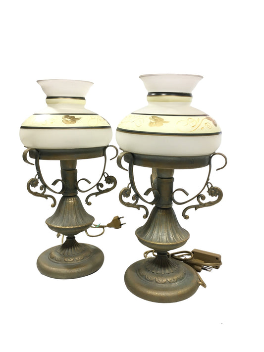 Set di 2 lampade in stile classico in metallo di colore oro e verde (effetto verderame), coppe in vetro sabbiato decorate a mano. Corredate di cavo con interruttore, funzionano con una lampadina attacco piccolo E14 (non incluse). Dimensioni: cm 18 x 37 h - base cm 14. In negozio e online su tuttochic.live