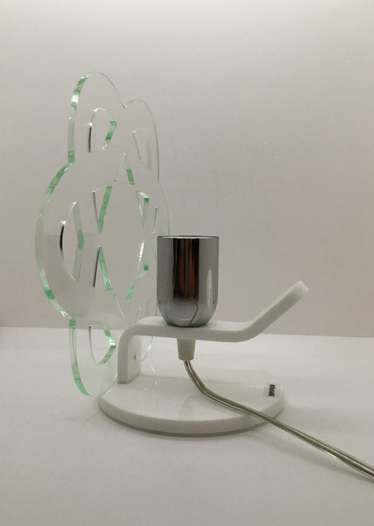Lampada da tavolo in metacrilato trasparente con profilo verde soft. Base e supporto in metacrilato bianco e portalampadina in metallo cromato. Si può applicare qualsiasi lampadina con attacco filettato E 27 (non inclusa). Dimensioni: cm 23 x 23 x 15 p. In negozio e online su tuttochic.live