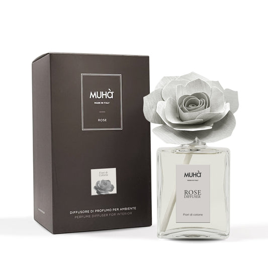 Profumatore d'ambiente Muhà Rose Diffuser Fiori di Cotone in flacone grande squadrato di vetro trasparente con essenza limpida, etichetta verticale grigio perla e diffusore artigianale a forma di rosa in legno color grigio chiarissimo desaturato, Tutto Chic.