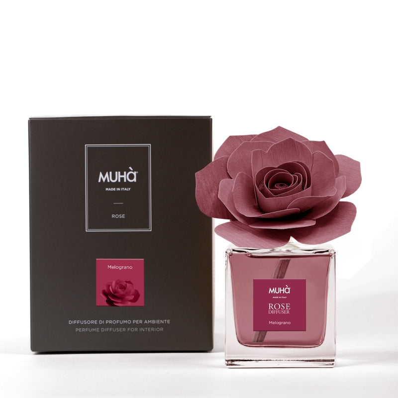 rofumatore d'ambiente Muhà Rose Diffuser Melograno in flacone squadrato di vetro trasparente con essenza fruttata, etichetta quadrata bordeaux e diffusore artigianale a forma di rosa in legno rosso melograno, Tutto Chic.