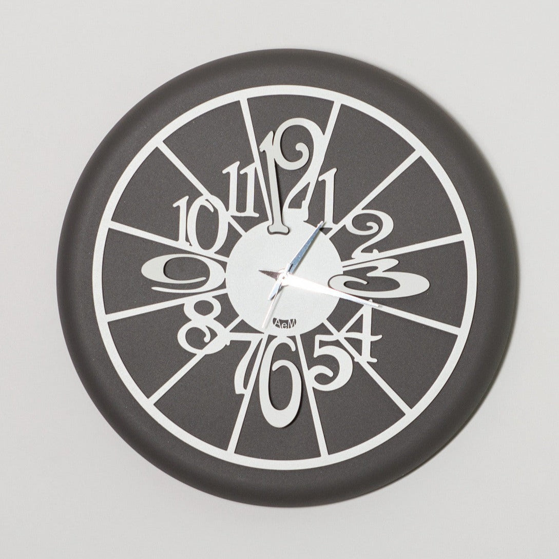 Orologio da parete di dimensione contenute, simpatico e divertente, fondo di colore ardesia, facile da collocare in cucina. Dimensioni: diam.30. In negozio e online su tuttochic.live