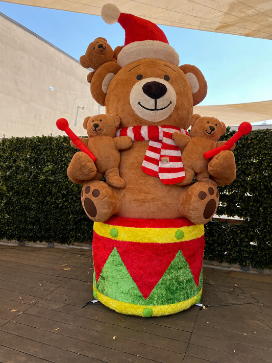 Maxi orso gonfiabile natalizio da esterno EDG alto 280 cm con rivestimento soffice effetto peluche, seduto su un tamburo festivo con orsetti piccoli e luci LED.