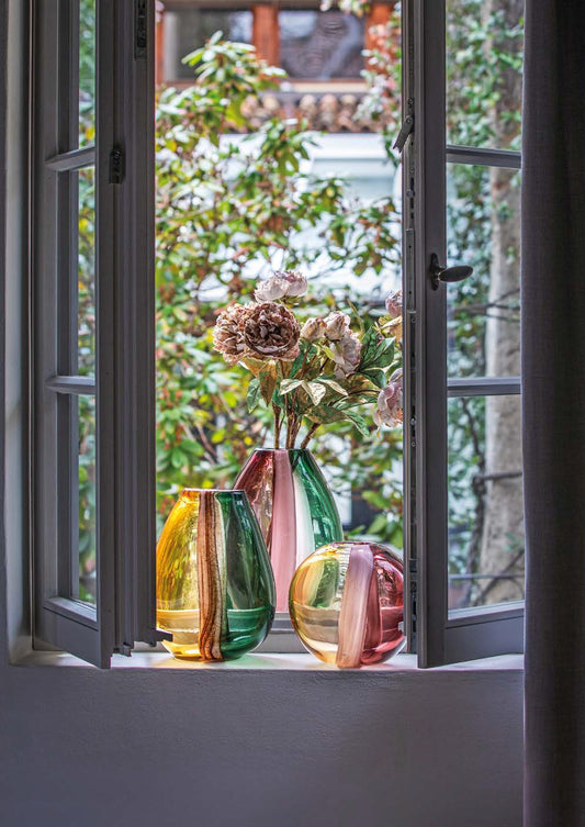 Il Vaso in vetro della collezione "Sullatela" di Rituali Domestici è un'opera d'arte per accogliere i tuoi fiori più preziosi. Realizzato in vetro borosilicato con sfumature rosa, questo vaso è elegante e raffinato. Dimensioni: cm 21 x 13 x 28 h. In negozio e online su tuttochic.live