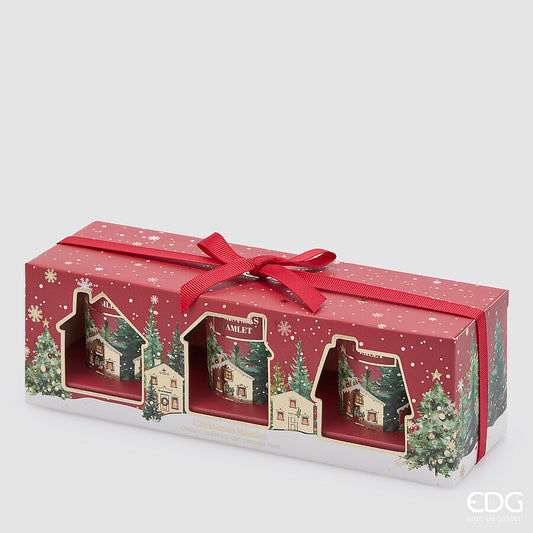 Confezione regalo natalizia rossa con nastro e dettagli oro contenente 3 candele in bicchiere di vetro rosso con illustrazioni di un villaggio innevato, marchio EDG Enzo De Gasperi.