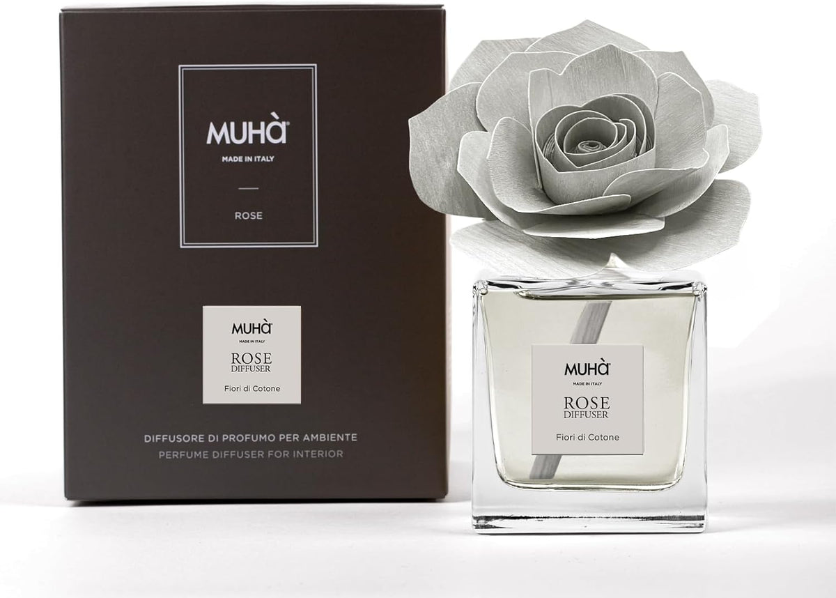 Profumatore d'ambiente Muhà Rose Diffuser Fiori di Cotone in flacone squadrato di vetro trasparente con essenza cristallina, etichetta centrale quadrata grigio perla e diffusore artigianale a forma di rosa in legno grigio chiarissimo, Tutto Chic.