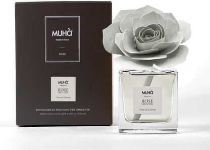 Profumatore d'ambiente Muhà Rose Diffuser Fiori di Cotone in flacone squadrato di vetro trasparente con essenza cristallina, etichetta centrale quadrata grigio perla e diffusore artigianale a forma di rosa in legno grigio chiarissimo, Tutto Chic.