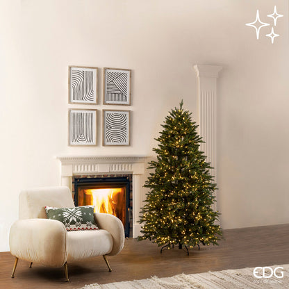 Albero di Natale artificiale Pino Cristallo EDG Enzo De Gasperi H 180 cm con 1500 mini LED a luce calda integrati e telecomando, posizionato in un salotto moderno accanto a una poltrona e un camino.