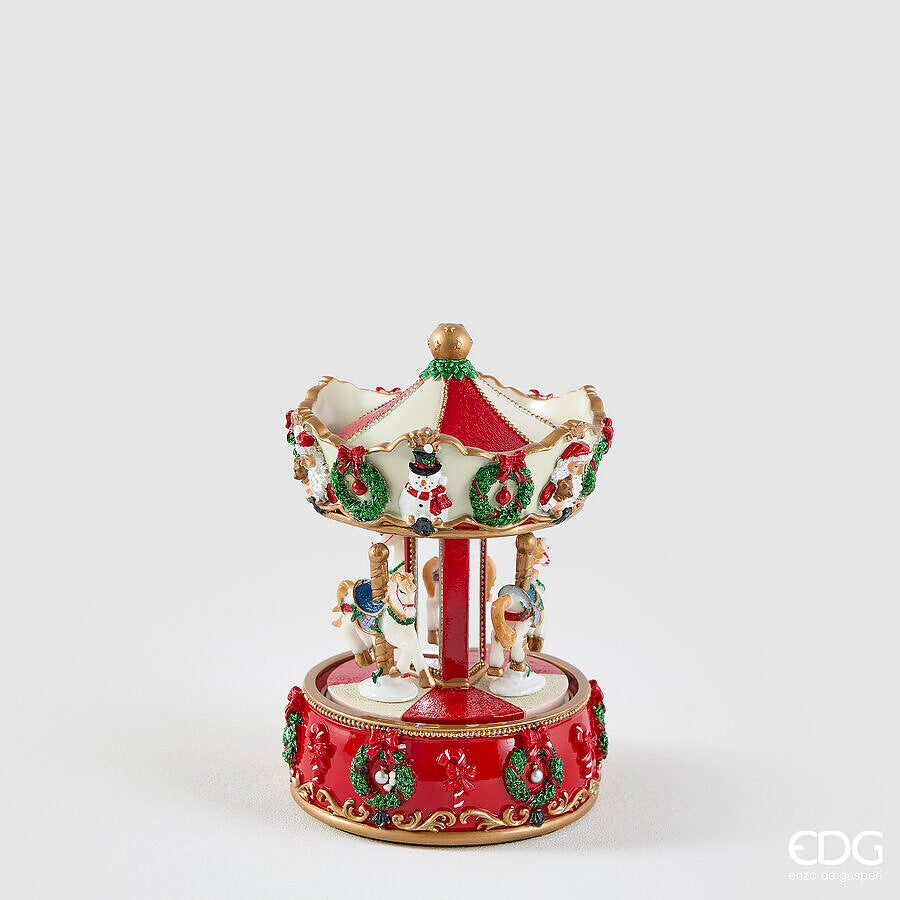 Carillon natalizio a forma di giostra con cavalli rotanti firmato EDG Enzo De Gasperi, altezza 17 cm. Struttura decorata in bianco e rosso con ghirlande natalizie, pupazzi di neve e cavallini da parata.