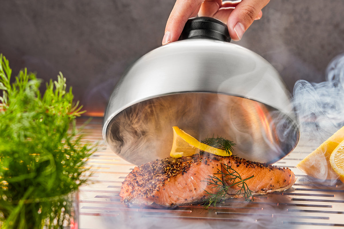 Campana per barbecue in acciaio inox con impugnatura nera, ideale per sciogliere formaggio su hamburger o affumicare cibi.