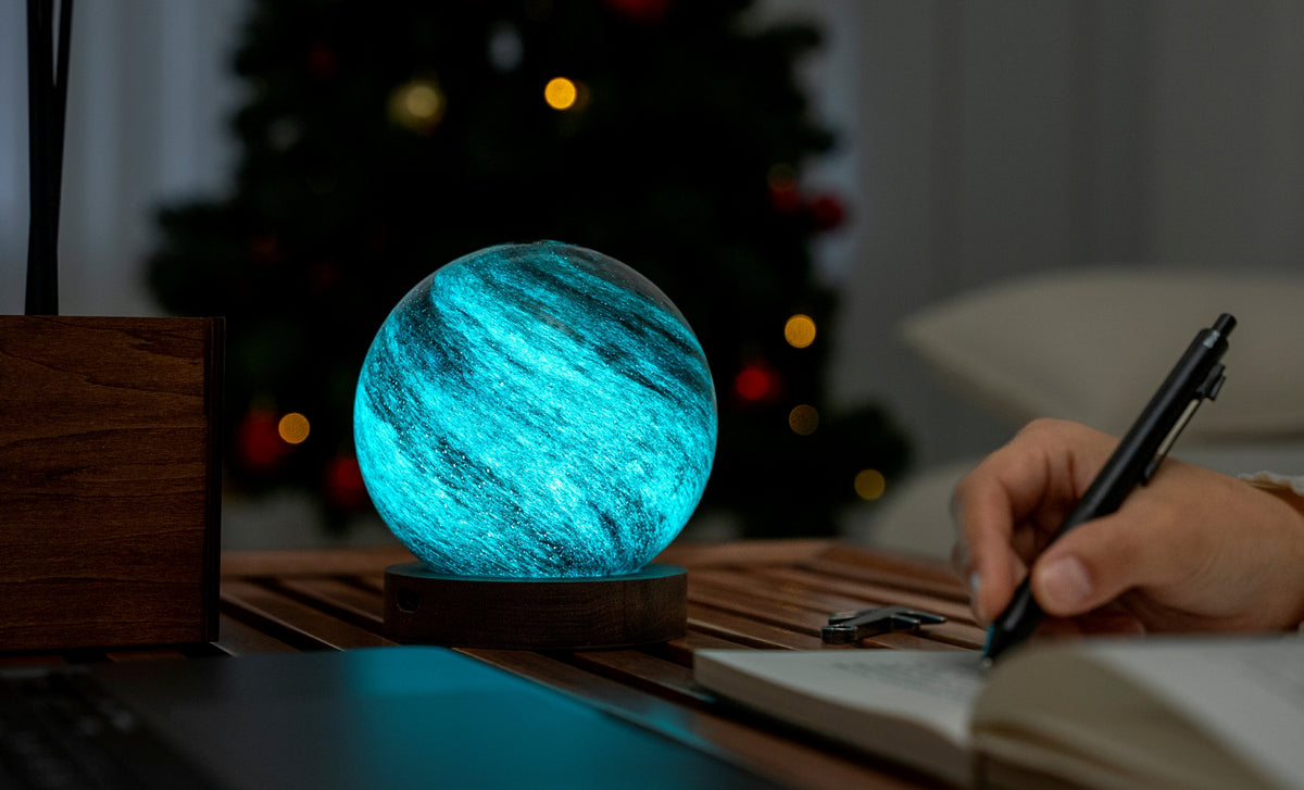 lampada AstraGlass Light. Composta da una sfera in vetro soffiata e dipinta a mano poggiata su una base rotonda in legno di noce americano. Questa lampada è perfetta per chiunque sia affascinato dal meraviglioso fenomeno naturale del nostro mondo. Dimensioni: cm ø 12 x h 13. In negozio e online su tuttochic.live