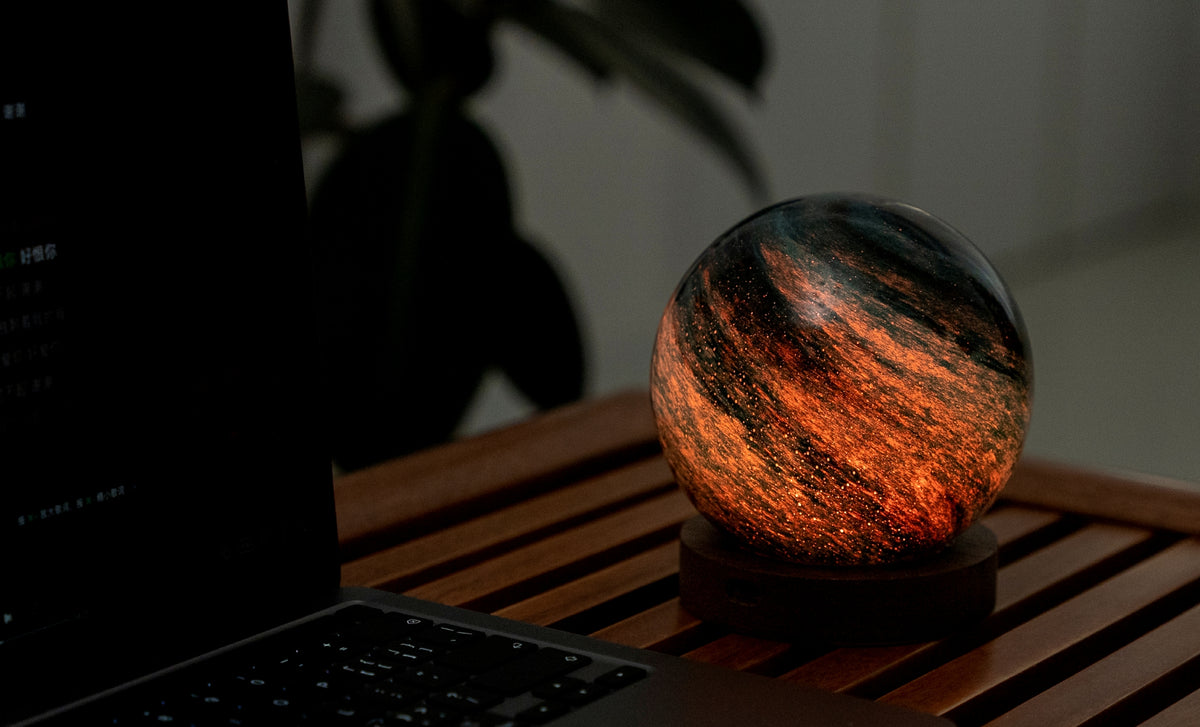 lampada AstraGlass Light. Composta da una sfera in vetro soffiata e dipinta a mano poggiata su una base rotonda in legno di noce americano. Questa lampada è perfetta per chiunque sia affascinato dal meraviglioso fenomeno naturale del nostro mondo. Dimensioni: cm ø 12 x h 13. In negozio e online su tuttochic.live