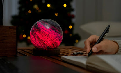 lampada AstraGlass Light. Composta da una sfera in vetro soffiata e dipinta a mano poggiata su una base rotonda in legno di noce americano. Questa lampada è perfetta per chiunque sia affascinato dal meraviglioso fenomeno naturale del nostro mondo. Dimensioni: cm ø 12 x h 13. In negozio e online su tuttochic.live