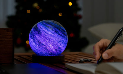lampada AstraGlass Light. Composta da una sfera in vetro soffiata e dipinta a mano poggiata su una base rotonda in legno di noce americano. Questa lampada è perfetta per chiunque sia affascinato dal meraviglioso fenomeno naturale del nostro mondo. Dimensioni: cm ø 12 x h 13. In negozio e online su tuttochic.live