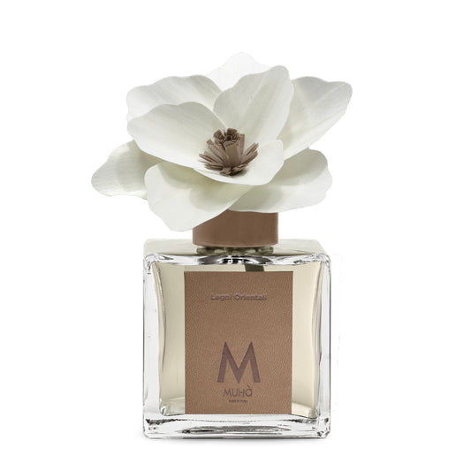 Diffusore d’ambiente con bottiglia in vetro con tappo in zama si accompagna a una magnolia in legno di betulla per diffondere la fragranza Legni Orientali. tuttochic.live