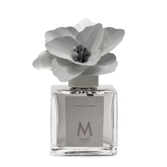 Diffusore d’ambiente con bottiglia in vetro con tappo in zama si accompagna a una magnolia in legno di betulla per diffondere la fragranza Fiori di Cotone. tuttochic.live