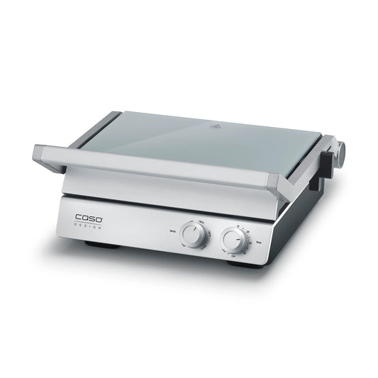 Piastra elettrica SteakChef CASO Design aperta su tavolo da cucina con bistecche in cottura