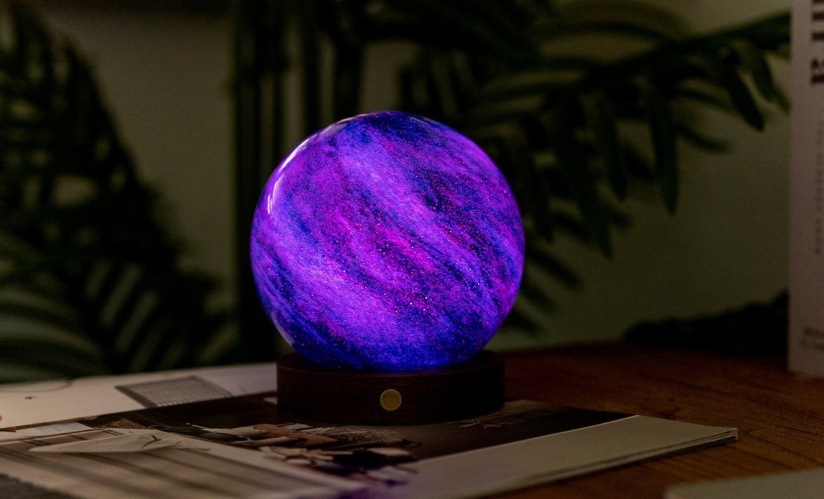 lampada AstraGlass Light. Composta da una sfera in vetro soffiata e dipinta a mano poggiata su una base rotonda in legno di noce americano. Questa lampada è perfetta per chiunque sia affascinato dal meraviglioso fenomeno naturale del nostro mondo. Dimensioni: cm ø 12 x h 13. In negozio e online su tuttochic.live