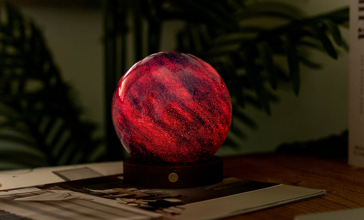 lampada AstraGlass Light. Composta da una sfera in vetro soffiata e dipinta a mano poggiata su una base rotonda in legno di noce americano. Questa lampada è perfetta per chiunque sia affascinato dal meraviglioso fenomeno naturale del nostro mondo. Dimensioni: cm ø 12 x h 13. In negozio e online su tuttochic.live