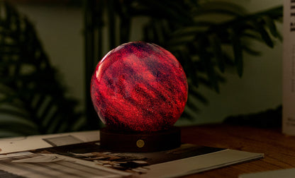 lampada AstraGlass Light. Composta da una sfera in vetro soffiata e dipinta a mano poggiata su una base rotonda in legno di noce americano. Questa lampada è perfetta per chiunque sia affascinato dal meraviglioso fenomeno naturale del nostro mondo. Dimensioni: cm ø 12 x h 13. In negozio e online su tuttochic.live