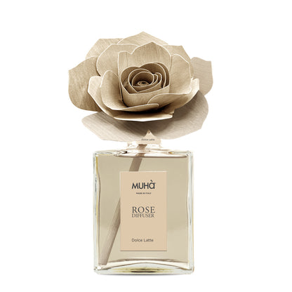 Profumatore d'ambiente Muhà Rose Diffuser Dolce Latte in flacone grande squadrato di vetro trasparente con essenza color crema, etichetta verticale beige e diffusore artigianale a forma di rosa in legno color panna, Tutto Chic.