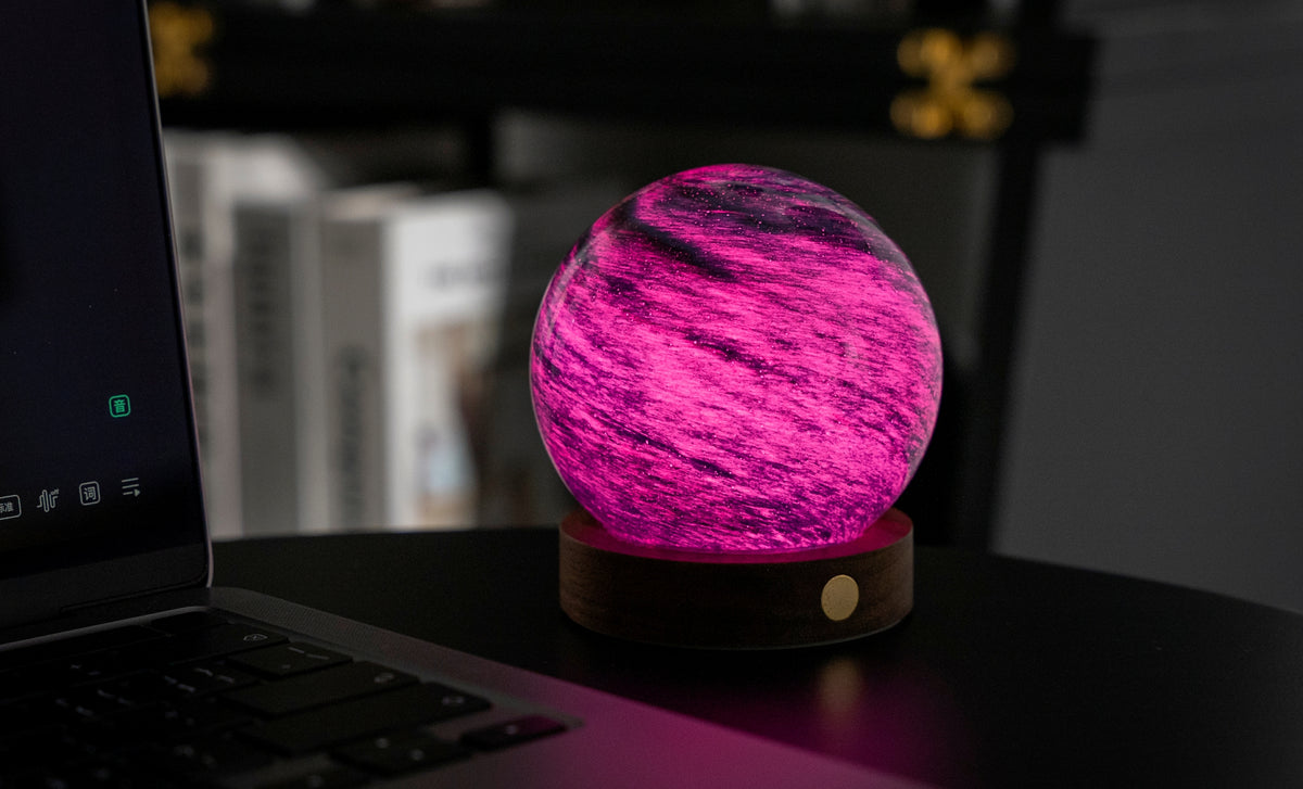 lampada AstraGlass Light. Composta da una sfera in vetro soffiata e dipinta a mano poggiata su una base rotonda in legno di noce americano. Questa lampada è perfetta per chiunque sia affascinato dal meraviglioso fenomeno naturale del nostro mondo. Dimensioni: cm ø 8 x h 9. In negozio e online su tuttochic.live