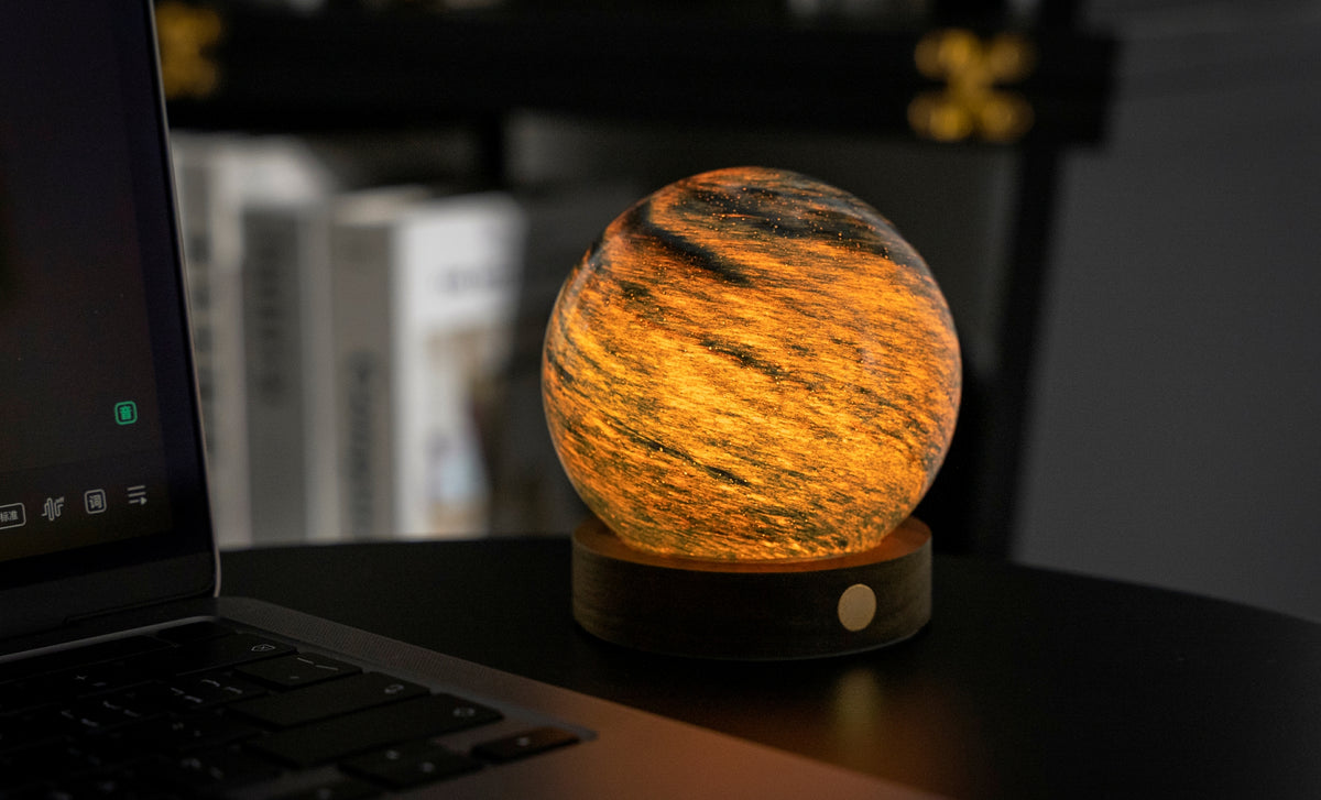 lampada AstraGlass Light. Composta da una sfera in vetro soffiata e dipinta a mano poggiata su una base rotonda in legno di noce americano. Questa lampada è perfetta per chiunque sia affascinato dal meraviglioso fenomeno naturale del nostro mondo. Dimensioni: cm ø 8 x h 9. In negozio e online su tuttochic.live