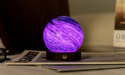 lampada AstraGlass Light. Composta da una sfera in vetro soffiata e dipinta a mano poggiata su una base rotonda in legno di noce americano. Questa lampada è perfetta per chiunque sia affascinato dal meraviglioso fenomeno naturale del nostro mondo. Dimensioni: cm ø 8 x h 9. In negozio e online su tuttochic.live