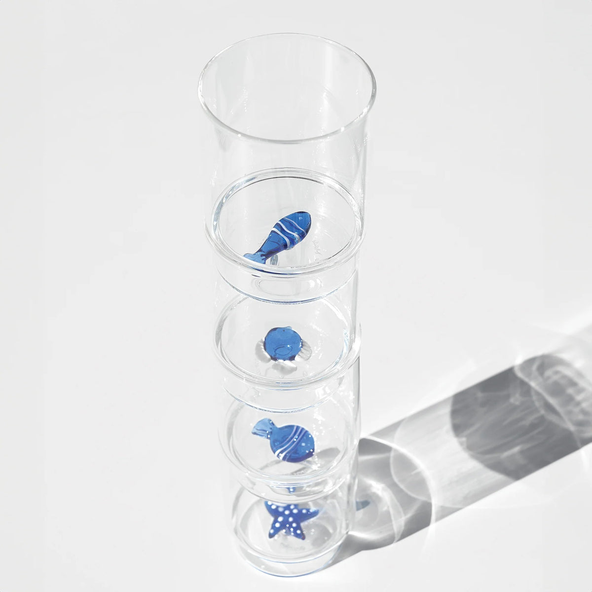 Il set Teca Mare è composto da 6 bicchieri contenenti sei diversi decori a tema “marino”, di colore bianco/blu: la stella di mare, il riccio di mare, il corallo, la sardina, il pesce palla e il pesce bicolore, tutti realizzati a mano. Dimensioni: Ø 8x h 10,5 cm - 35 cl. In negozio e online su tuttochic.live