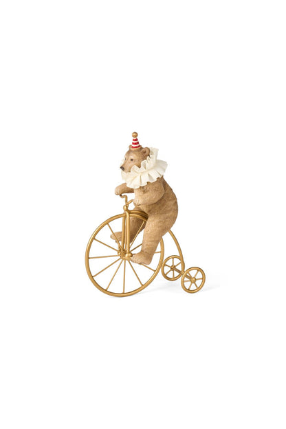 Statuina natalizia decorativa in resina a forma di orsetto marrone chiaro da circo con colletto bianco, mentre pedala su un antico biciclo vintage color oro lucido, altezza 25,5 cm, collezione Velvet Luxury Nuvole di Stoffa, Tutto Chic.