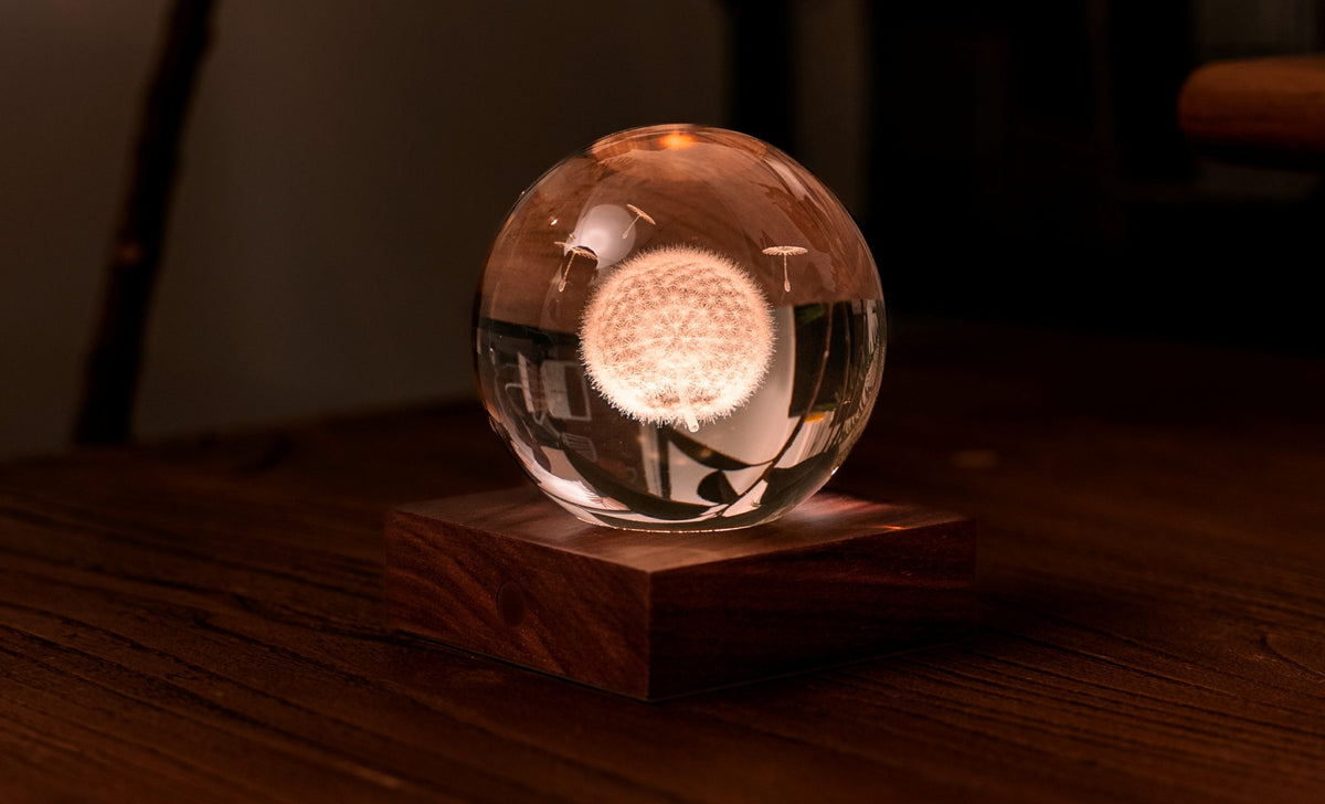 La lampada composta da una sfera in cristallo con decoro interno inciso al laser in 3D su una base quadrata in legno massello di noce naturale. Dimensioni: cm 8 x 8 x h 9,. In negozio e online su tuttochic.live