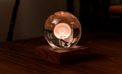 La lampada composta da una sfera in cristallo con decoro interno inciso al laser in 3D su una base quadrata in legno massello di noce naturale. Dimensioni: cm 8 x 8 x h 9,. In negozio e online su tuttochic.live