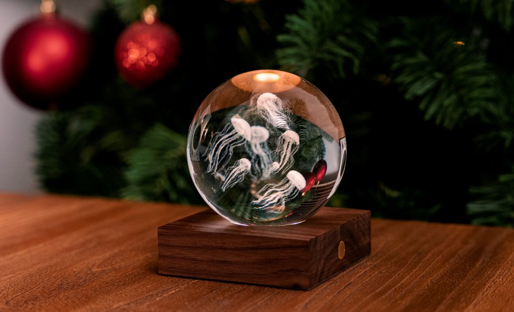 La lampada composta da una sfera in cristallo con decoro interno inciso al laser in 3D su una base quadrata in legno massello di noce naturale. Dimensioni: cm 8 x 8 x h 9,. In negozio e online su tuttochic.live