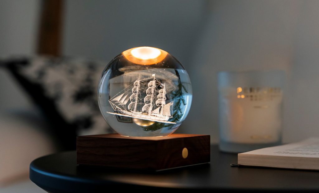 La lampada composta da una sfera in cristallo con decoro interno inciso al laser in 3D su una base quadrata in legno massello di noce naturale. Dimensioni: cm 8 x 8 x h 9,. In negozio e online su tuttochic.live