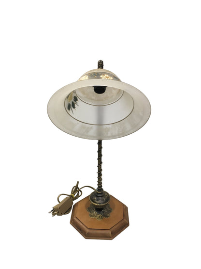 Lampada da tavolo in stile classico con braccetto in metallo di colore bronzo e oro, base in legno di forma ottagonale e coppa in vetro sabbiato decorato a mano, funziona con una lampadina attacco piccolo E14 (non inclusa). Dimensioni: cm 25 x 40,5 h - base cm 16 x 16. In negozio e online su tuttochic.live