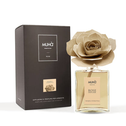 Profumatore d'ambiente Muhà Rose Diffuser Vaniglia e Ambra pura in flacone grande squadrato di vetro trasparente con essenza dorata, etichetta verticale ambra chiaro e diffusore artigianale a forma di rosa in legno color ocra tenue, Tutto Chic.