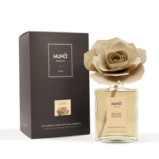 Profumatore d'ambiente Muhà Rose Diffuser Vaniglia e Ambra pura in flacone grande squadrato di vetro trasparente con essenza dorata, etichetta verticale ambra chiaro e diffusore artigianale a forma di rosa in legno color ocra tenue, Tutto Chic.