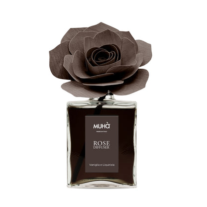 Profumatore d'ambiente Muhà Rose Diffuser Vaniglia e Liquirizia in flacone grande squadrato di vetro trasparente con essenza scura, etichetta verticale marrone e diffusore artigianale a forma di rosa in legno color cioccolato fondente, Tutto Chic.