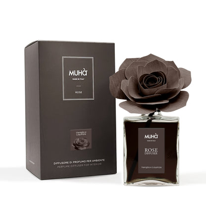 Profumatore d'ambiente Muhà Rose Diffuser Vaniglia e Liquirizia in flacone grande squadrato di vetro trasparente con essenza scura, etichetta verticale marrone e diffusore artigianale a forma di rosa in legno color cioccolato fondente, Tutto Chic.