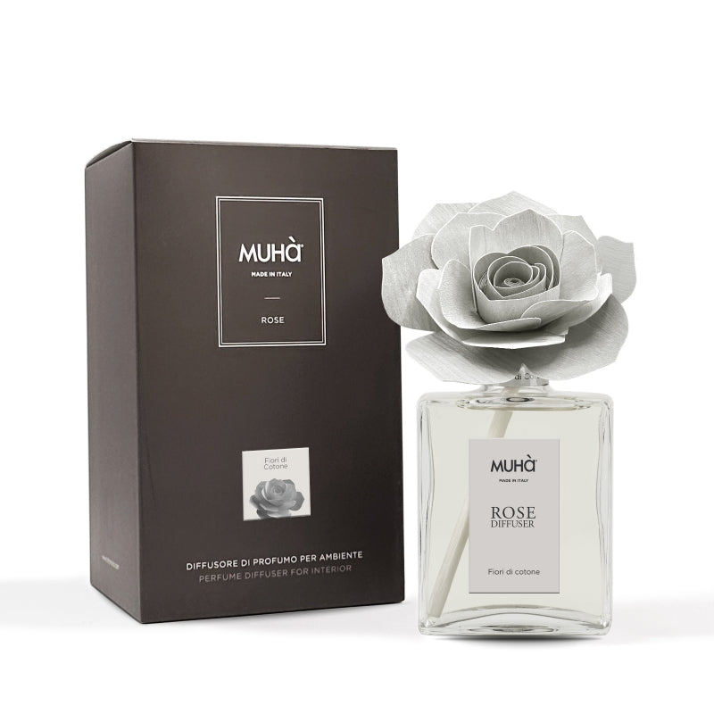 Profumatore d'ambiente Muhà Rose Diffuser Fiori di Cotone in flacone grande squadrato di vetro trasparente con essenza limpida, etichetta verticale grigio perla e diffusore artigianale a forma di rosa in legno color grigio chiarissimo desaturato, Tutto Chic.