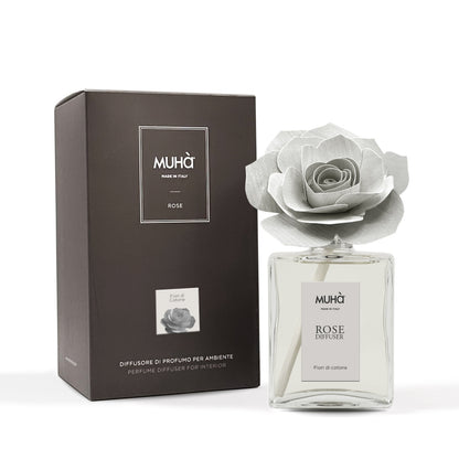 Profumatore d'ambiente Muhà Rose Diffuser Fiori di Cotone in flacone grande squadrato di vetro trasparente con essenza limpida, etichetta verticale grigio perla e diffusore artigianale a forma di rosa in legno color grigio chiarissimo desaturato, Tutto Chic.