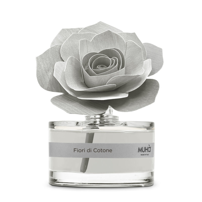 Profumatore d'ambiente Muhà Rosa Diffuser Fiori di Cotone in boccetta di vetro trasparente con essenza grigio chiaro, etichetta argento e diffusore artigianale a forma di rosa in legno grigio perla, Tutto Chic.