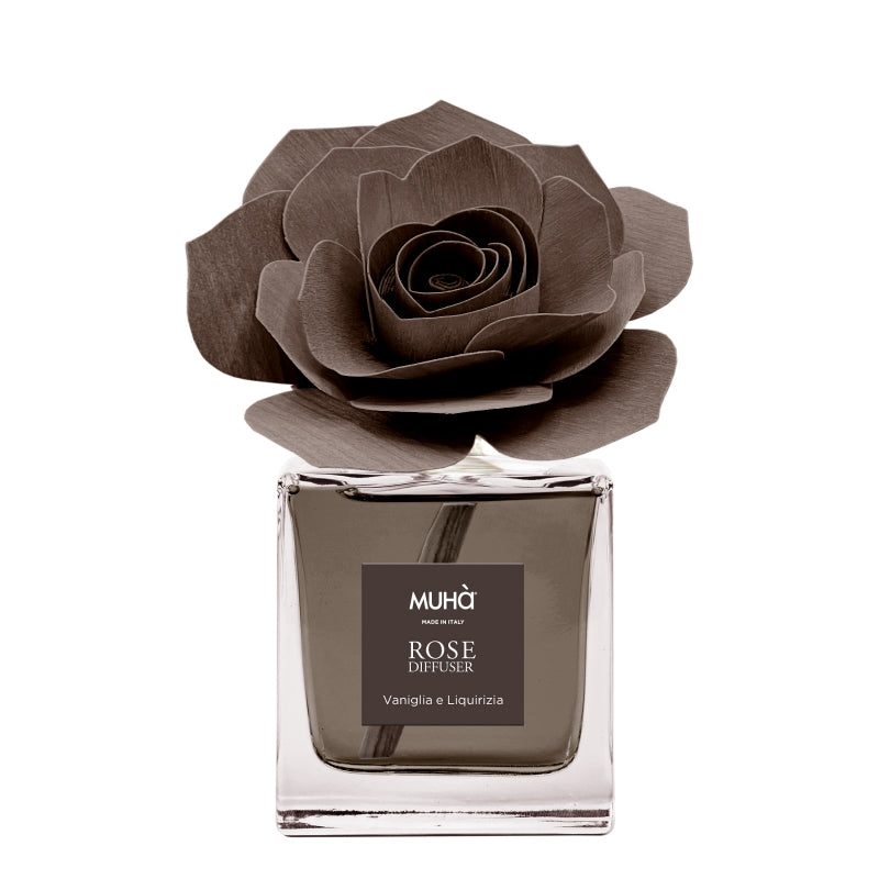 Profumatore d'ambiente Muhà Rose Diffuser Vaniglia e Liquirizia in flacone squadrato di vetro trasparente con essenza marrone, etichetta quadrata centrale e diffusore artigianale a forma di rosa in legno marrone testa di moro, Tutto Chic.