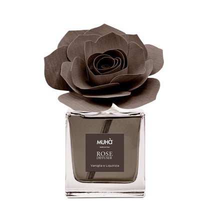 Profumatore d'ambiente Muhà Rose Diffuser Vaniglia e Liquirizia in flacone squadrato di vetro trasparente con essenza marrone, etichetta quadrata centrale e diffusore artigianale a forma di rosa in legno marrone testa di moro, Tutto Chic.