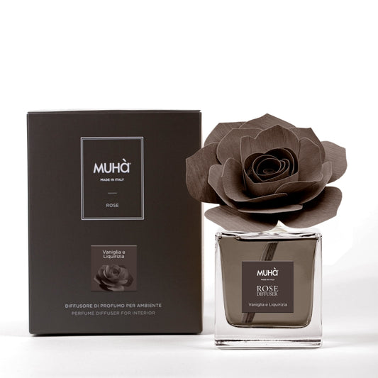 Profumatore d'ambiente Muhà Rose Diffuser Vaniglia e Liquirizia in flacone squadrato di vetro trasparente con essenza marrone, etichetta quadrata centrale e diffusore artigianale a forma di rosa in legno marrone testa di moro, Tutto Chic.