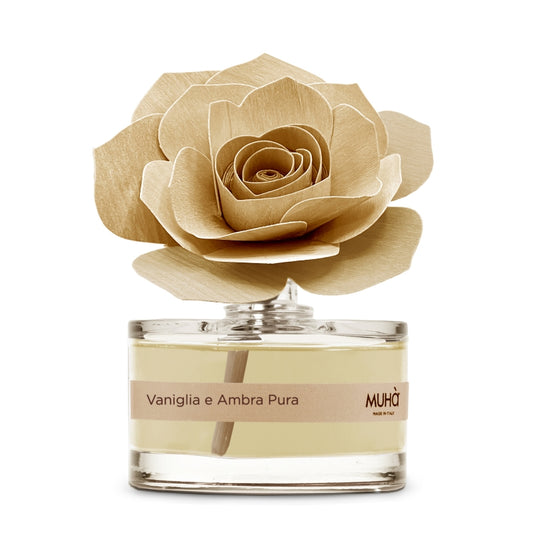 Profumatore d'ambiente Muhà Rosa Diffuser Vaniglia e Ambra Pura in boccetta di vetro trasparente con essenza dorata, etichetta beige e diffusore artigianale a forma di rosa in legno ocra chiaro, Tutto Chic.