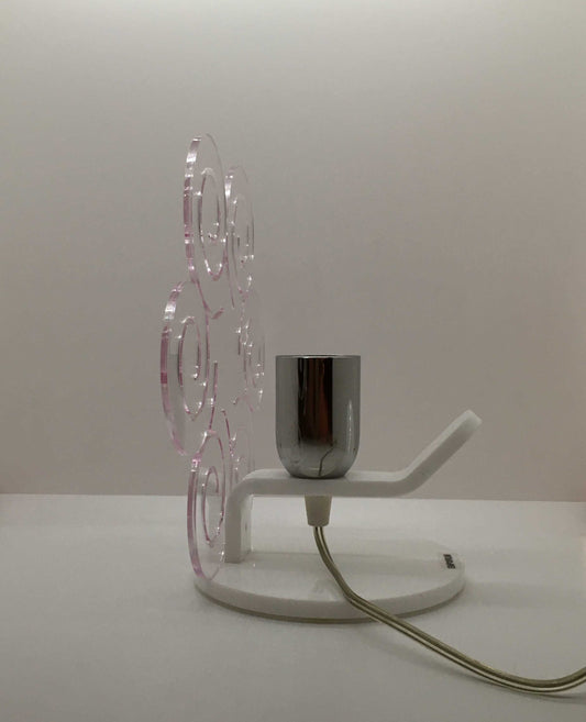 Lampada da tavolo in metacrilato trasparente con profilo viola soft. Base e supporto in metacrilato bianco e portalampadina in metallo cromato. Si può applicare qualsiasi lampadina con attacco filettato E 27 (non inclusa). Dimensioni: cm 23 x 23 x 15 p. In negozio e online su tuttochic.live